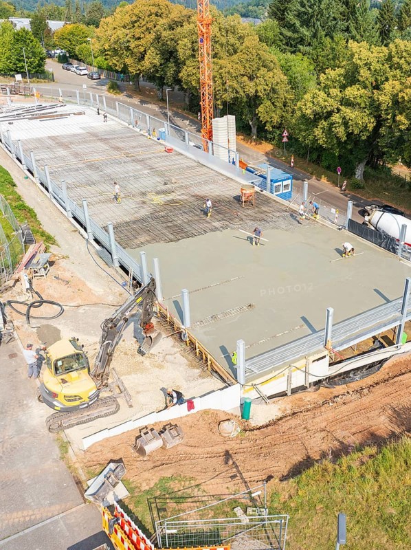 Workers and machines concreting on a construction site under a large crane, car park construction, Calw, Germany