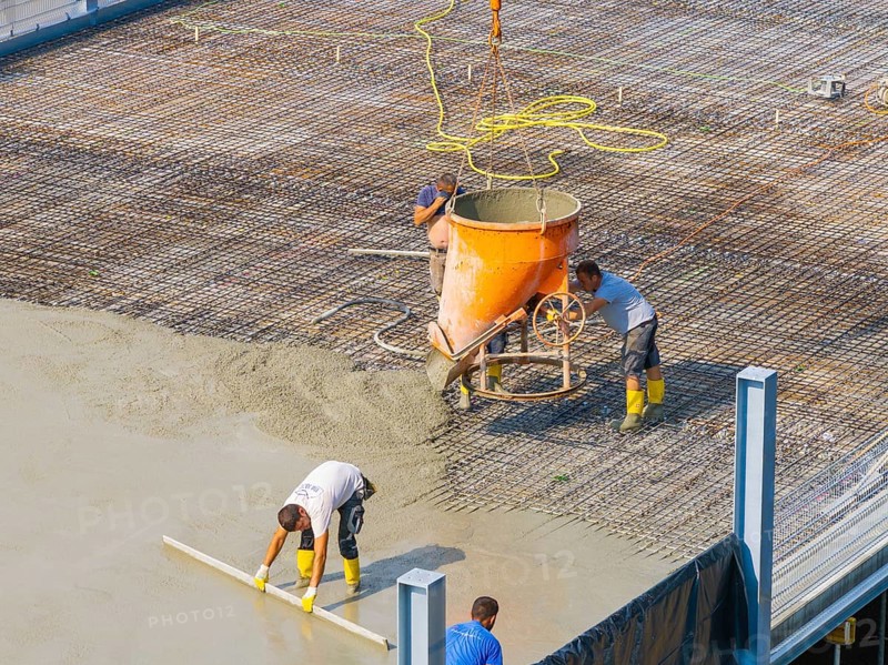 Close-up of workers concreting on a construction site under a crane, car park construction, Calw, Germany