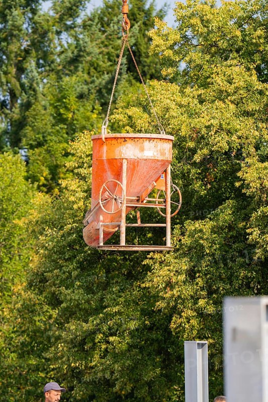 Concrete mixer being lifted with a crane on a construction site near trees, car park construction, Calw, Germany