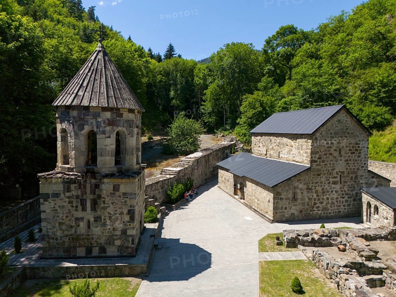 Stone chapel with adjoining buildings in a forest landscape under a clear blue sky, aerial view, Chitakhevi Church of St George, The Green Monastery, Mtsvane Monastery, Samtskhe-Javakheti region, Georgia