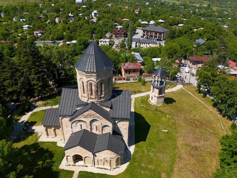 Aerial view of a church with surrounding buildings and green vegetation in a village, aerial view, Nikorzminda Cathedral, Nikorzminda Cathedral, Racha-Lechkhumi region, Lower Svaneti, Georgia