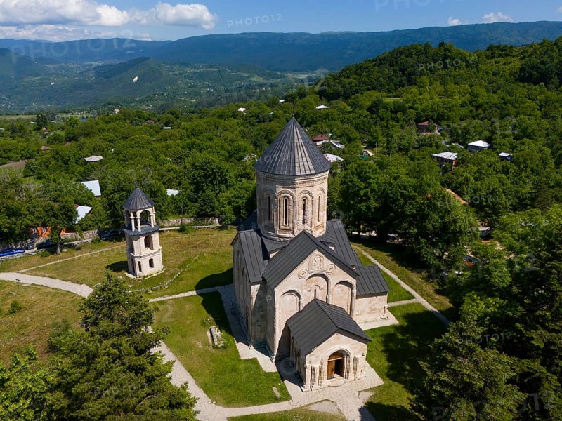 Traditional church surrounded by green landscape and hilly surroundings under blue sky, aerial view, Nikorzminda Cathedral, Nikorzminda Cathedral, Racha-Lechkhumi region, Lower Svaneti, Georgia