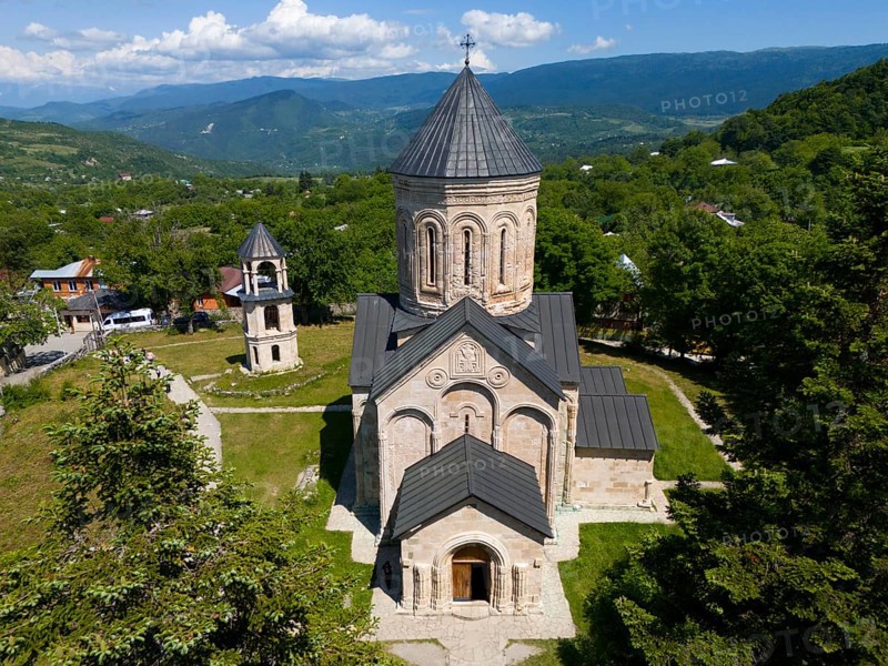Historic church in a green mountain landscape under a blue sky with clouds, aerial view, Nikorzminda Cathedral, Nikorzminda Cathedral, Racha-Lechkhumi region, Lower Svaneti, Georgia