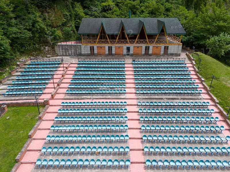 An amphitheatre with many rows of seats and a covered stage against a wooded backdrop, aerial view, Green Theatre, Tsageri, Racha-Lechkhumi region and Lower Svaneti, Georgia