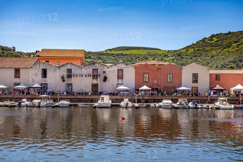 Sardinia, boats in the river Temo and residential buildings on the promenade, guests at the restaurants with outdoor catering, Bosa, Europe, province of Oristano, Italy, architecture, atmosphere, outdoor area, outdoor catering, boats, relaxation, food, river Temo, riverbank, leisure, building, guests, sky, culture, midday, afternoon, promenade, travel, restaurants, shade, sightseeing, seating, summer, city, tourism, tourists, drinking, urban, holiday, water, residential, European, historic, picturesque, Mediterranean, sunny