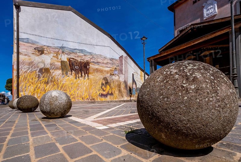 Sardinia, stone balls in front of a house with mural (Murales) Sardinia sight, Tinnura, Europe, Province of Oristano, Italy, architecture, attraction, outdoor, design, detail, village, heritage, facade, open-air, building, house, culture, art, artist, murals, travel photography, destinations, sight, sightseeing, stone, stone balls, street view, symbolism, tourism, mural, brick, colourful, decoration, inviting, unique, European, historical, creative, cultural, artistic, rural, picturesque, Mediterranean, regional, traditional, public art
