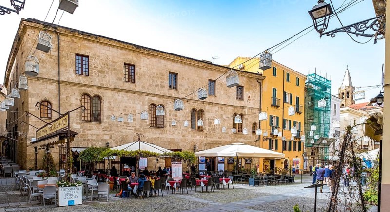 Sardinia, tourist tour group in the old town with sandstone-coloured palazzi, birdcage from house to house over the street, Alghero, Europe, Province of Sassari, Italy, lighting, IT, travel, destination, Ristorante Pizzeria Forno A Legna, sightseeing, tourism, tourist, tourist attraction, tourist trip, birdcage, tourist destination