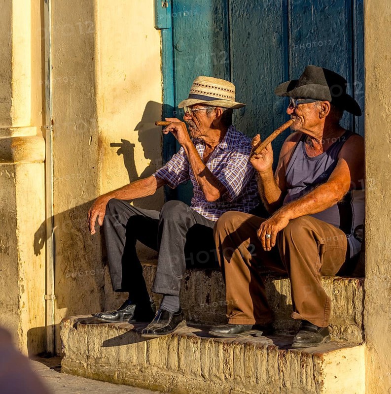 Two old Cubans smoking cigars and sitting on a staircase in the warm light of the sunset, Trinidad, Cuba, Sancti Spíritus, Sancti Spíritus