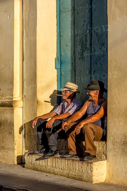 Two old Cubans smoking cigars and sitting on a staircase in the warm light of the sunset, Trinidad, Cuba, Sancti Spíritus, Sancti Spíritus