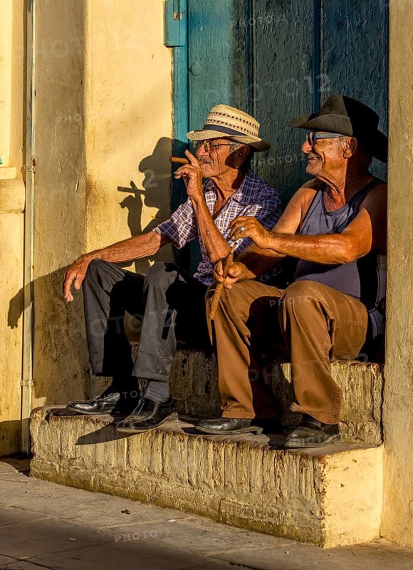 Two old Cubans smoking cigars and sitting on a staircase in the warm light of the sunset, Trinidad, Cuba, Sancti Spíritus, Sancti Spíritus