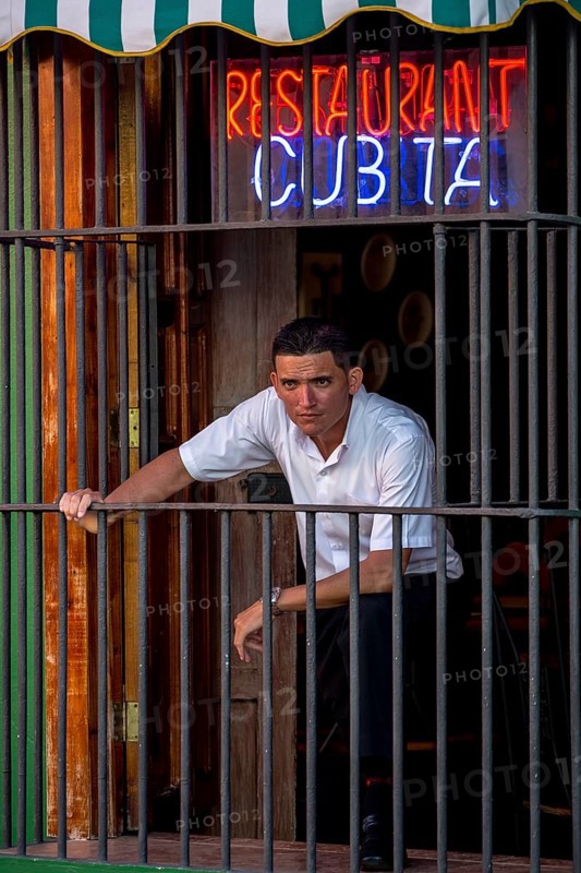 Waiter waiting for customers behind the window bars of the Cubita Restaurant, Trinidad, Cuba, Sancti Spíritus, Sancti Spíritus