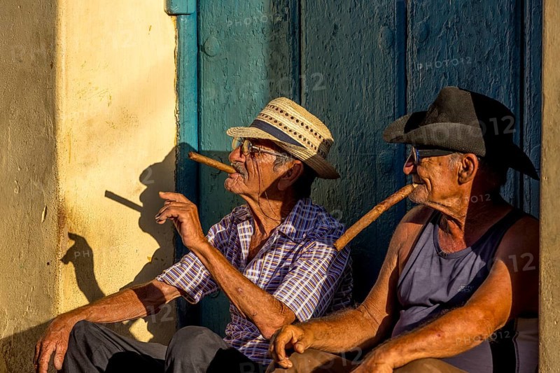 Two old Cubans smoking cigars and sitting on a staircase in the warm light of the sunset, Trinidad, Cuba, Sancti Spíritus, Sancti Spíritus
