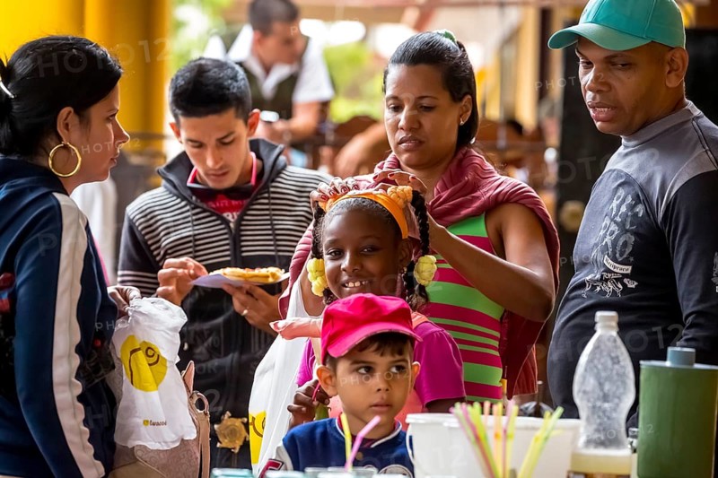 Young girl with pinned-up pigtails at a Cuban pizza stand with her family, Viñales, Cuba, Pinar del Río, Viñales, Pinar del Río
