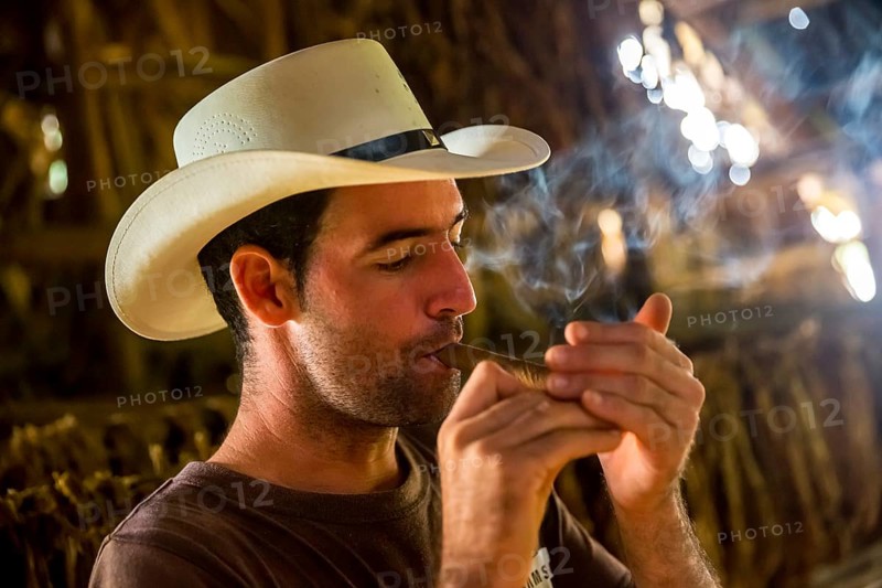 Tobacco farmer, tobacco farmer Luis Manne Alvares Rodrigues lights a Havana cigar, tobacco farm in the Vinales Valley, Viñales, Cuba, Pinar del Río, Viñales, Pinar del Río