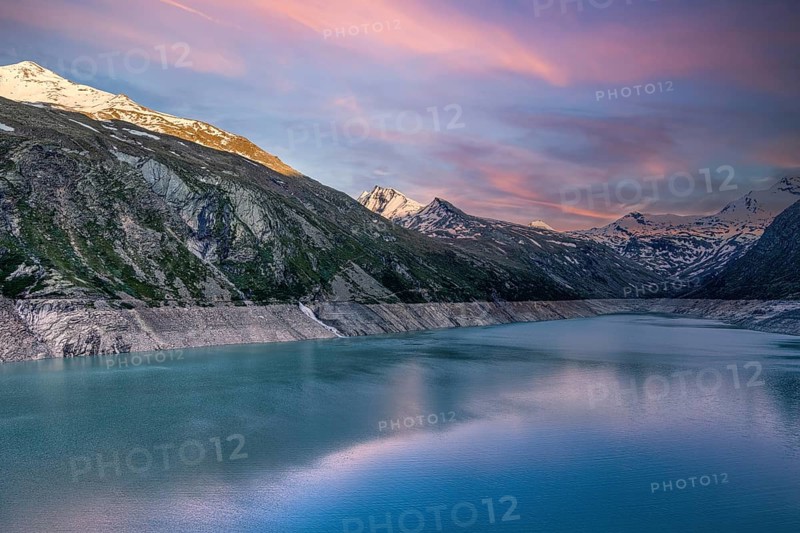 Early morning light over a lake with snow-covered mountains and pink sky, Mattmark reservoir, Saas Almagell, Saas Grund, Canton Valais, Switzerland