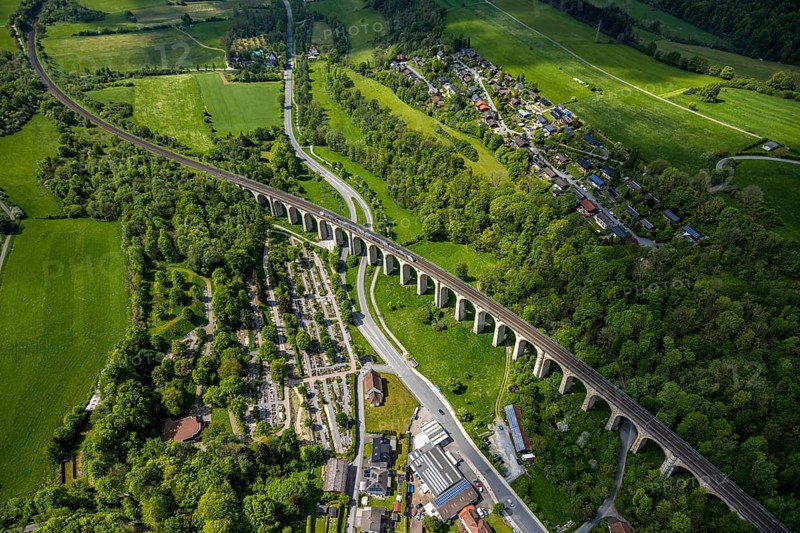 Aerial view, Altenbekener Viaduct, Adenauerstraße, railway viaduct Bridge structure, also called Bekeviaduct or Great Viaduct, suburban railway, Altenbeken cemetery and cross chapel on the road Alter Kirchweg, residential area Am Stapelsberg, meadows and fields, Altenbeken, East Westphalia, North Rhine-Westphalia, Germany, railway viaduct, bridge structure, Beke Viaduct, Great Viaduct, Altenbeken cemetery, Kreuzkapelle, Alter Kirchweg, residential area, Am Stapelsberg, meadows, fields, landscape, architecture, traffic, rail transport, railway, infrastructure, building, history, historical, rural, nature, living, green spaces, village, town, perspective, sky, outdoor area