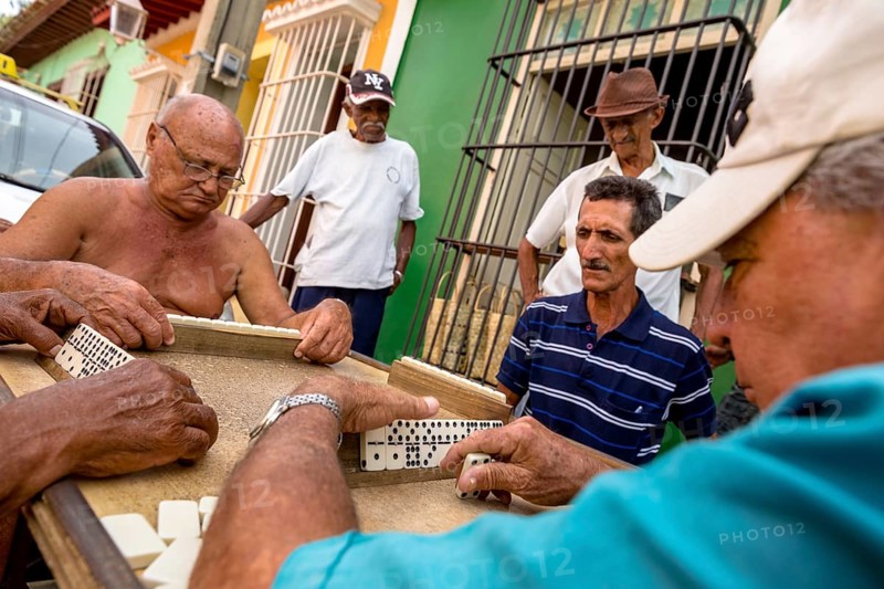 Old Cubans playing dominoes at a table on the street in the city centre of Trinidad, Trinidad, Cuba, Sancti Spíritus, Cuba, Sancti Spíritus