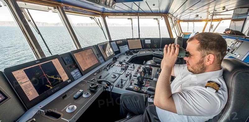 MS Polarlys, command bridge, officer on bridge, Honningsvåg, Finnmark, Norway, Scandinavia, Europe, adventure travel, binoculars, tourism, Honningsvåg, Hurtigruten, Hurtigruten voyage, command post, cruise, cruise ship, NOR, navigation technology, travel, destination, ship, shipping, ship's bridge, ship's officer, sea voyage, sighting, sightseeing, controls, tourism, Norwegian, Scandinavian, touristic