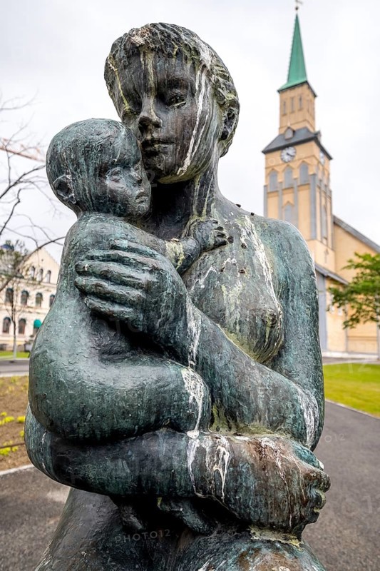 Statue Mother and Child, Church Square, Tromsø Cathedral in the background, Tromsø, Troms, Norway, Scandinavia, Europe, adventure travel, place of worship, Bankgata, woman and child, tourism, religious community, place of worship, sacred site, Hurtigruten, Hurtigruten voyage, church, church community, denomination, cruise, NOR, travel, destination, religion, religious site, sea voyage, sightseeing, Storgata, tourism, Tromsø, Tromsø domkirke, Norwegian, Scandinavian, touristic