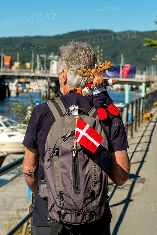 Tourist with backpack and cloth cup and Norwegian flag, travel guide, tour guide, tourist guid, Trondheim, Trøndelag, Norway, Scandinavia, Europe, adventure travel, tourism, Hurtigruten, Hurtigrutenreise, cruise, NOR, travel, destination, sea voyage, sightseeing, tourism, Trøndelag, Norwegian, Scandinavian, touristic