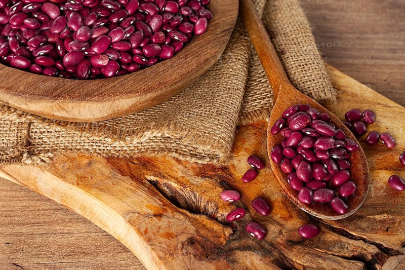 Red beans, laid out in a wooden bowl, on a chopping board, rustic style, covered with burlap, top view, close-up