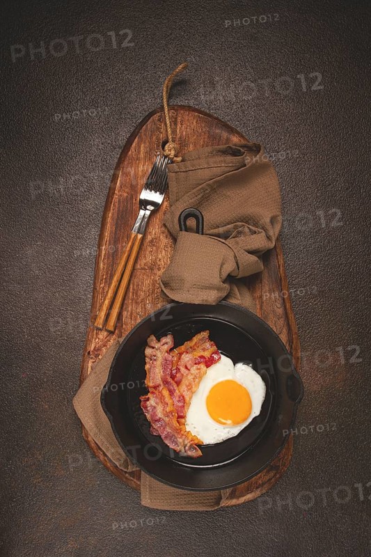 Fried egg with bacon, in a cast-iron pan, breakfast, top view, close-up, homemade, no people