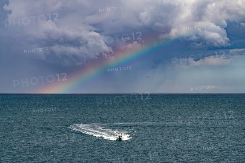 Rainbow over the Adriatic Sea and motorboat near Polignano a Mare, Apulia, Italy