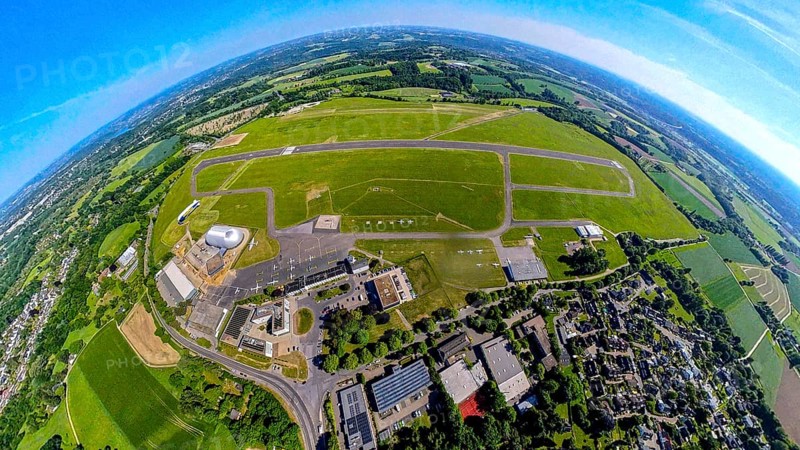 Aerial view, Essen-Mülheim airfield with runway and landing strip, airship and airship hangar, construction site and new office buildings with multi-storey car park (Pitstop-Zenrale), globe, fisheye image, 360 degree image, tiny world, little planet, fisheye image, Holthausen - Southeast, Mülheim an der Ruhr, Ruhr area, North Rhine-Westphalia, Germany, DE, Europe, fisheye lens, fisheye lens, airport, airfield, runway, aerial photography, aerial photography, aerial photography, Mülheim, runway, super wide angle lens, overview, bird's eye view, birds-eyes view, fisheye lens, insta360 camera, overview