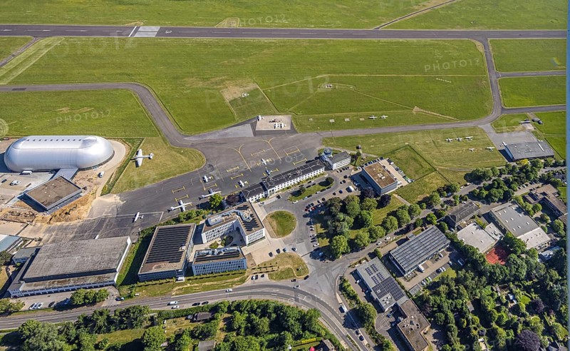 Aerial view, Essen/Mülheim Airport, construction site next to the WDL airship hangar, construction site and new office buildings with multi-storey car park (Pitstop centre), parked aircraft, runway and landing strip, Holthausen - south-east, Mülheim an der Ruhr, Ruhr area, North Rhine-Westphalia, Germany, construction work, construction area, building site, building plots, construction project, construction site, DE, Europe, aerial view, aerial photography, aerial photography, overview, bird's-eye view, overview