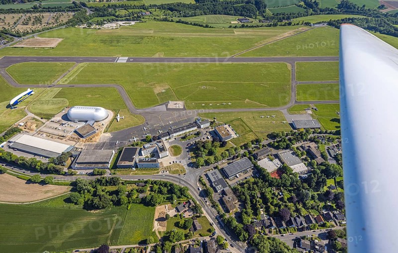 Aerial view, Essen/Mülheim Airport, Goodyear airship Zeppelin, construction site next to the WDL airship hangar, construction site and new office buildings with multi-storey car park (Pitstop centre), parked aircraft, runway and landing strip, Holthausen - Southeast, Mülheim an der Ruhr, Ruhr area, North Rhine-Westphalia, Germany, construction work, construction area, building site, building plots, construction project, construction site, DE, Europe, aerial view, aerial photography, aerial photography, overview, bird's-eye view, overview