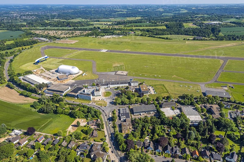 Aerial view, Essen/Mülheim Airport, Goodyear airship Zeppelin, construction site next to the WDL airship hangar, construction site and new office buildings with multi-storey car park (Pitstop centre), parked aircraft, runway and landing strip, Holthausen - Southeast, Mülheim an der Ruhr, Ruhr area, North Rhine-Westphalia, Germany, construction work, construction area, building site, building plots, construction project, construction site, DE, Europe, aerial view, aerial photography, aerial photography, overview, bird's-eye view, overview