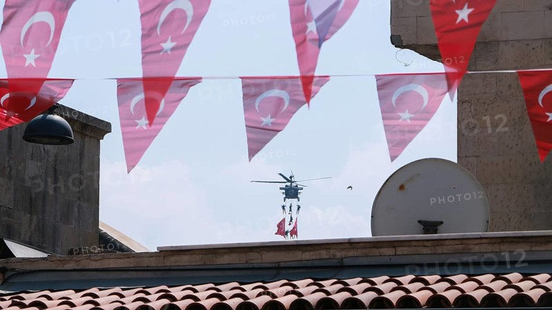 Türkiye special operations police hang from a helicopter with ropes, carrying weapons and unfurling a large Turkish flag while saluting citizens during an aerobatic air show at Teknofest technology festival. Gaziantep, Türkiye. September 24, 2020, Gaziantep, Gaziantep, Türkiye