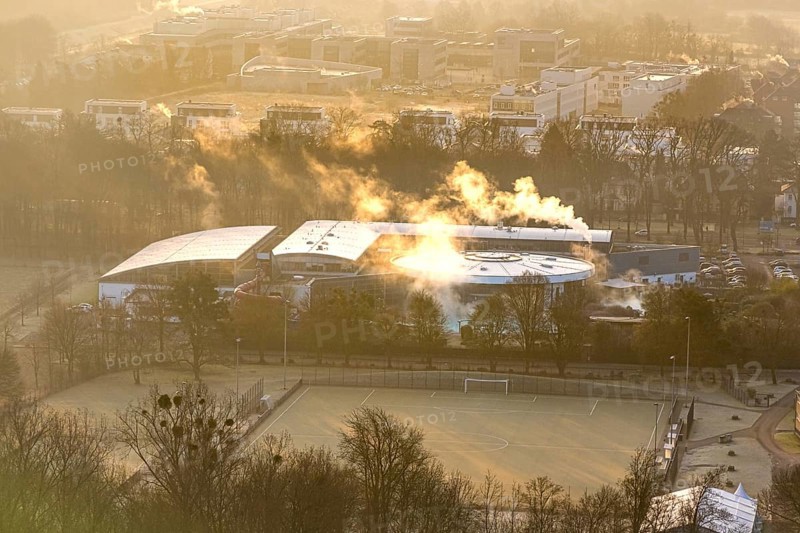 Aerial view, wintry Maximare adventure pool with indoor and outdoor pools with clouds of smoke, in front of it sports field football pitch of the sports centre east, in the back Hamm-Lippstadt University of Applied Sciences and Sci:Q Science Quarter Paracelsuspark, centre, Hamm, Ruhr area, North Rhine-Westphalia, Germany