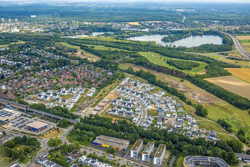 Aerial view, Duisburg-Süd, residential area Angerbogen, Am Alten Angerbach, semi-circular new housing estate, commercial area Xella International GmbH and Edeka E-Center Angerbogen, roofed railway station Angerbogen, behind the Rahmer See, Huckingen, Duisburg, Ruhr area, North Rhine-Westphalia, Germany