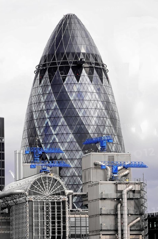The Gherkin or Swiss-Re-Tower, in front of a historic building, London, England, Great Britain, Modern skyscraper with characteristic glass facade and cranes in the background, London, England, Great Britain