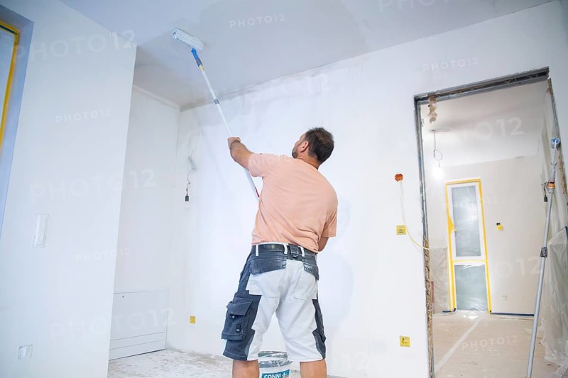 Wallpapering work: Priming the ceiling for the application of wallpaper