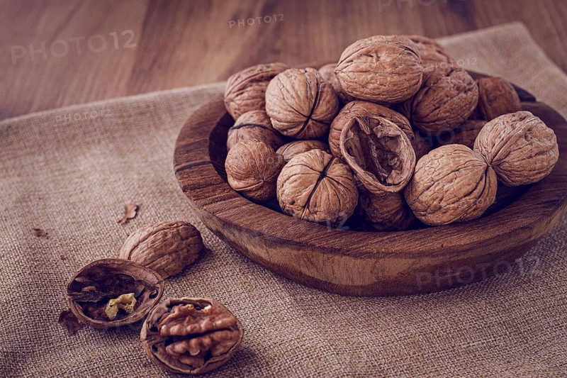 Freshly picked walnuts, in a wooden bowl, on a wooden table, rustic style, no people