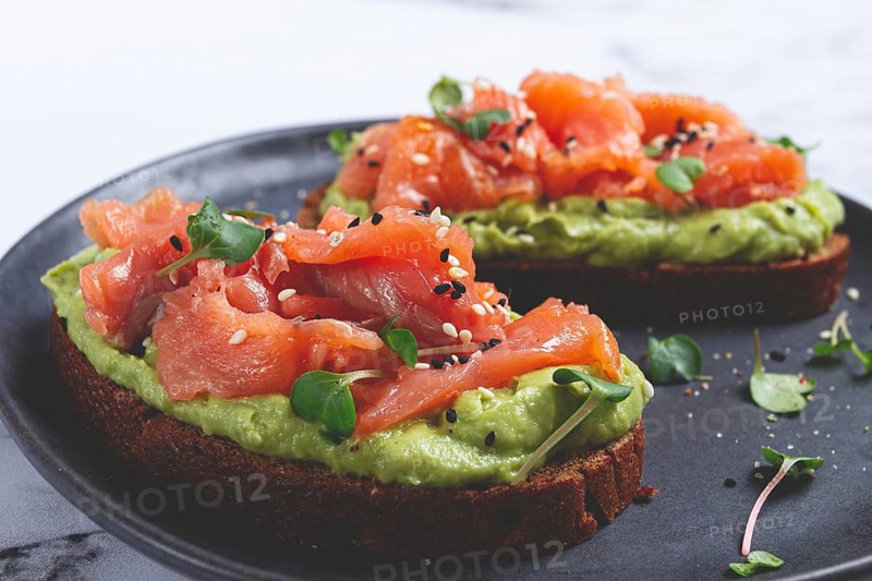 Breakfast, Sandwiches with smoked salmon and avocado, on dark rye bread, with microgreens, on a marble table, homemade, no people