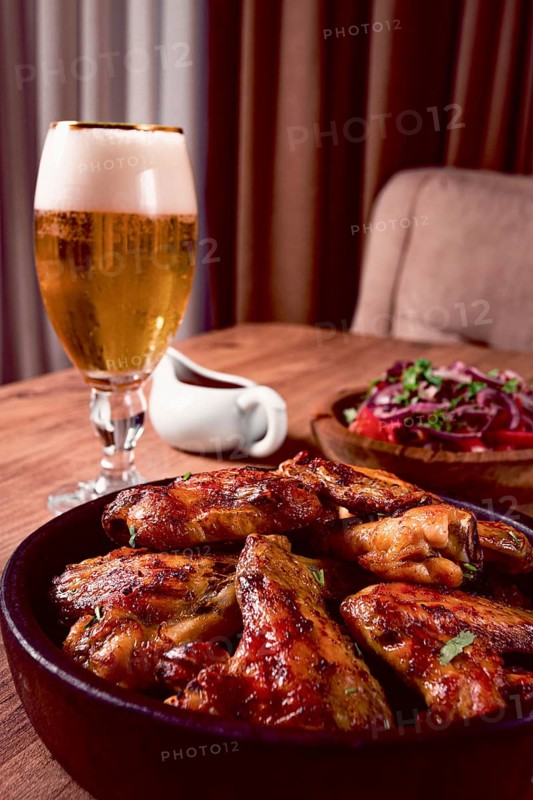 Delicious barbecue chicken wings, with French fries, salad and a refreshing drink, at a cozy table, there are no people