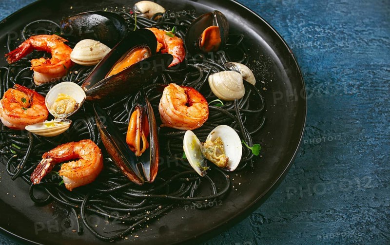 Black spaghetti, with shrimp and mussels, vongole, on a black plate, spaghetti with shrimp, spaghetti with mussels, top view, no people