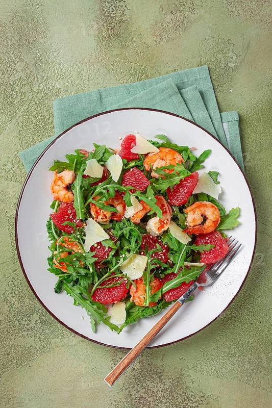 Fresh shrimp salad with arugula, grapefruit, and parmesan served in a bowl