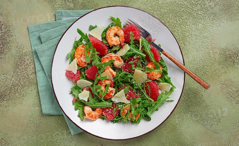 Fresh shrimp salad with arugula, grapefruit, and parmesan served in a bowl