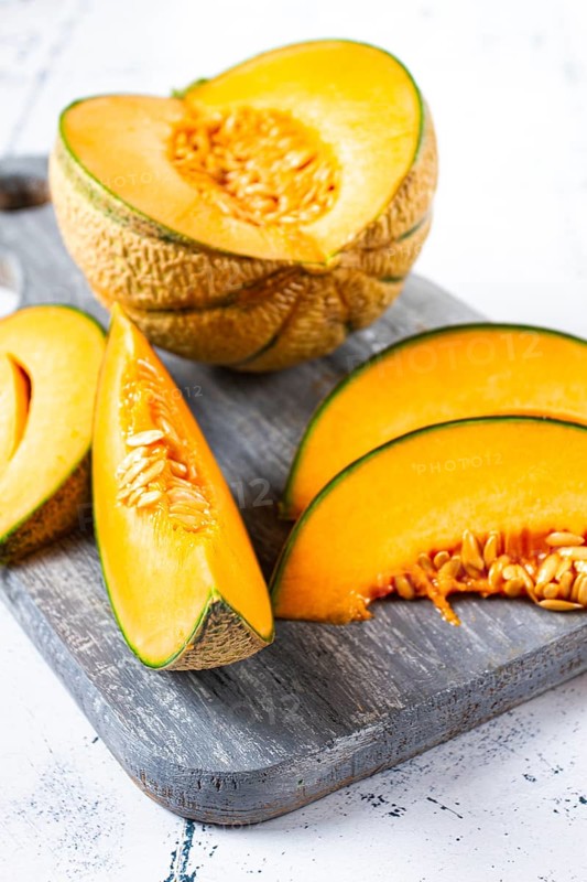 Freshly sliced melon slices, cantaloupe melon, on a wooden chopping board, close-up