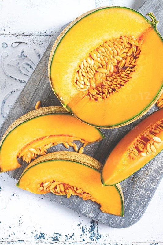 Freshly sliced melon slices, cantaloupe melon, on a wooden chopping board, close-up