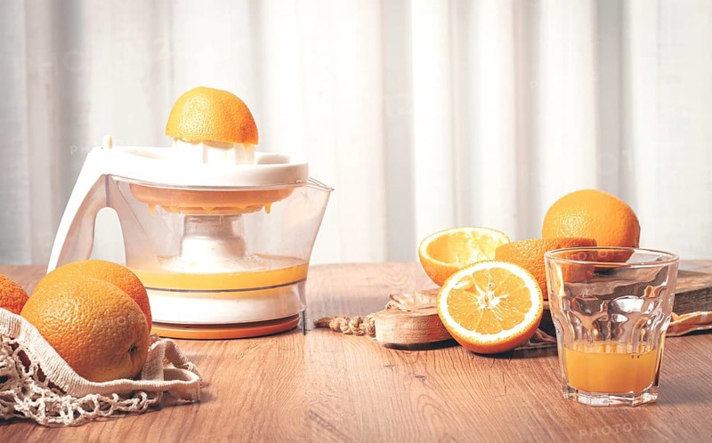 Preparation of freshly squeezed orange juice, using a juicer, in a cozy kitchen setting