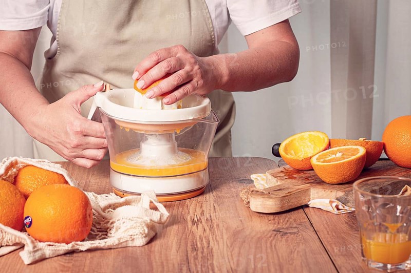 Preparation of freshly squeezed orange juice, using a juicer, in a cozy kitchen setting