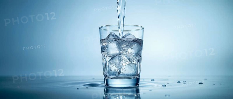 A glass of water with ice cubes being filled with a stream of water, set against a gradient blue backdrop, creating a fresh, refreshing vibe, AI generated