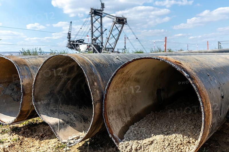Large excavator in open-cast mine with pipes in the foreground, Manheim, North Rhine-Westphalia, Germany