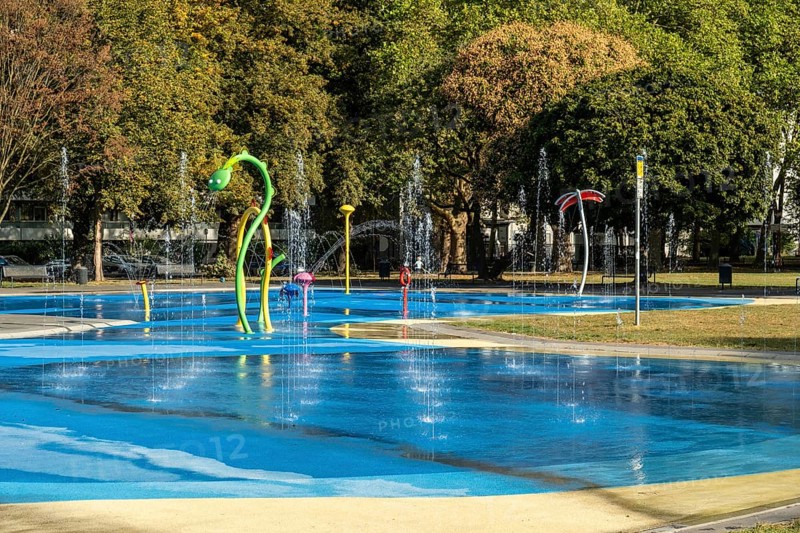Panorama water playground with colourful play equipment, green belt, Cologne