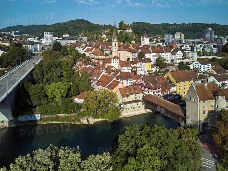 View of the old town with the parish church Maria Himmelfahrt, on the left the high bridge, behind the castle ruin Stein formerly an administrative centre of the Habsburgs, in front the river Limmat and the covered wooden bridge with the Landvogteischloss, Baden, Canton, Aargau, Switzerland